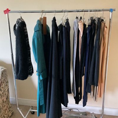 Sale Photo Thumbnail #155: Rolling metal clothing rack filled with women's coats, jackets, and pants, including a bright teal trench coat.