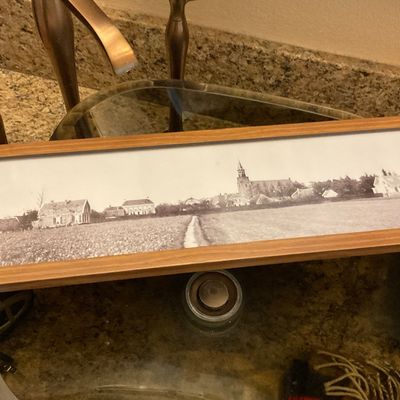 Sale Photo Thumbnail #161: Framed panoramic black-and-white photograph depicting a rural landscape with village houses and a church, presented in a slim wooden frame.