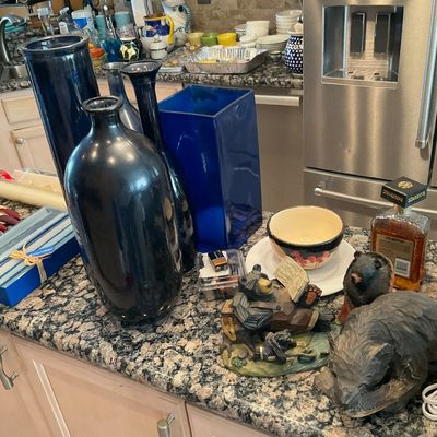 Sale Photo Thumbnail #112: Collection of decorative household items including large dark blue ceramic vases, carved bear figurines, box candles, and a bottle of Disaronno on a granite kitchen counter.