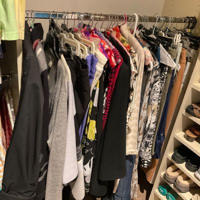 Sale Photo Thumbnail #167: Closet filled with hanging modern women's clothing, accompanied by a shoe rack holding various sandals, sneakers, and slippers.