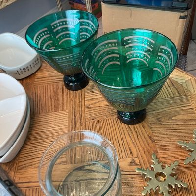 Sale Photo Thumbnail #123: Pair of emerald green footed glass bowls with etched geometric patterns, accompanied by clear glass stemware and brass snowflake candle holders.
