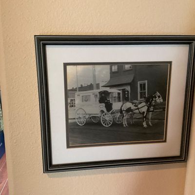 Sale Photo Thumbnail #64: Framed black-and-white photograph depicting a vintage horse-drawn carriage on a city street, presented in a dark wooden frame with a white mat.