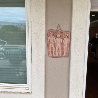 Sale Photo Thumbnail #14: Terracotta or clay wall plaque featuring three boys wearing cowboy hats, shown from behind in a high-relief style.