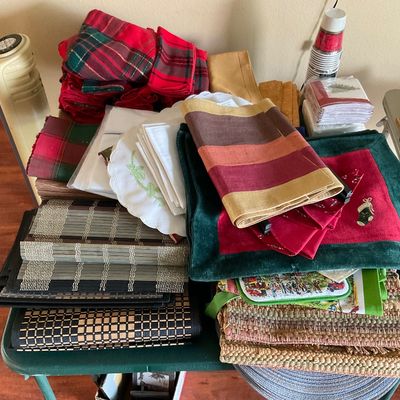 Sale Photo Thumbnail #70: Collection of assorted table linens, place mats, napkins, and holiday textiles arranged on a green folding table.