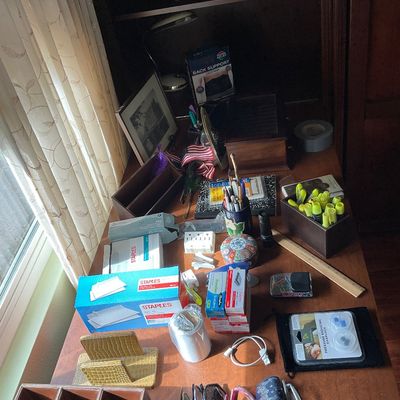 Sale Photo Thumbnail #66: Wooden desk cluttered with various office supplies, including boxes of Staples envelopes, highlighters, organizers, eyeglasses, and small collectibles.