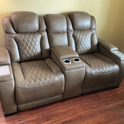 Sale Photo Thumbnail #51: Contemporary taupe leather dual-reclining home theater sofa featuring diamond-quilted backrests and seats, center console with cup holders, and armrest storage compartments.