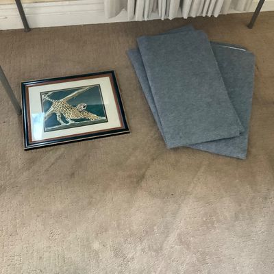 Sale Photo Thumbnail #148: Framed leopard print artwork resting on carpet alongside folded grey acoustic wall panels.
