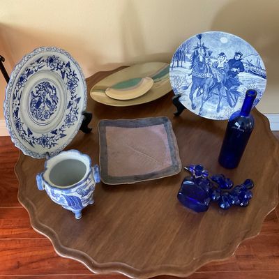 Sale Photo Thumbnail #82: Collection of decorative ceramics and cobalt blue glass tabletop items, including blue-and-white porcelain plates, a footed jar, a decorative horse plate, and a cobalt bottle with glass grapes.