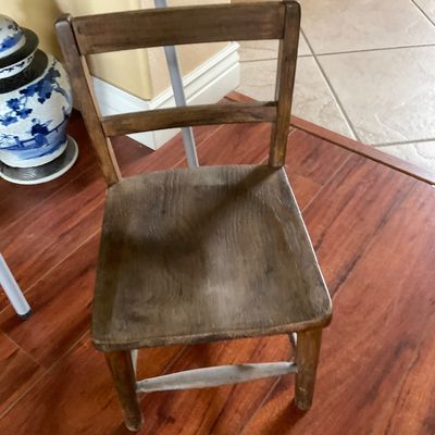 Sale Photo Thumbnail #89: Vintage small wooden child's chair featuring a ladder-back design and a naturally weathered dark finish.