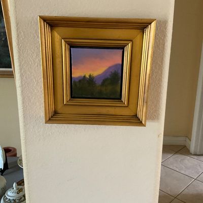 Sale Photo Thumbnail #90: Small framed landscape oil painting depicting a mountain sunset silhouette, housed in a deep gold-finished wooden frame.