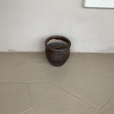 Sale Photo Thumbnail #17: Small dark brown glazed ceramic planter with a rounded body sitting on a patio.