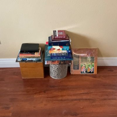 Sale Photo Thumbnail #56: Collection of books stacked on wooden and perforated metal risers, sitting alongside a framed classical art print on wood flooring.