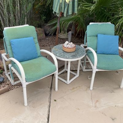 Sale Photo Thumbnail #25: Pair of white PVC outdoor armchairs with green fabric cushions and blue accent pillows, paired with a matching small round side table.
