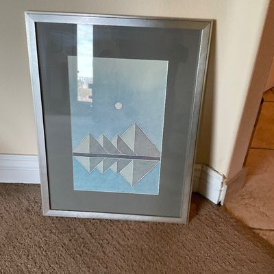 Sale Photo Thumbnail #157: Framed geometric artwork depicting a mountain landscape with reflections, presented in a silver metal frame with a dark grey mat.
