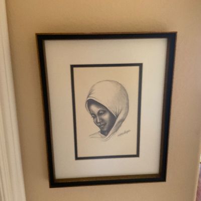 Sale Photo Thumbnail #63: Framed charcoal sketch portrait depicting a woman wearing a headscarf, presented in a black and gold frame with double matting.
