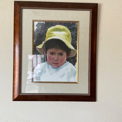 Sale Photo Thumbnail #152: Framed portrait painting depicting a child wearing a yellow sun hat, set within a double mat and rich mahogany-tone wooden frame.