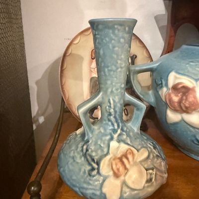 Vintage Roseville art pottery Magnolia pattern vase in blue featuring embossed floral details and handles.
