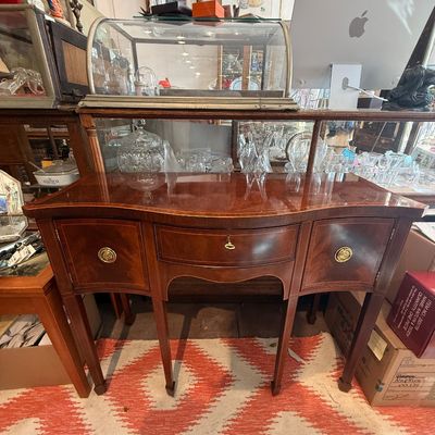 Antique Hepplewhite-style mahogany side sideboard with serpentine front, brass hardware, and central keyhole drawer.
