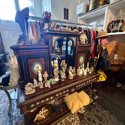 Ornate antique inlaid wood sideboard or server with a mirrored center section, displaying a collection of porcelain figurines.