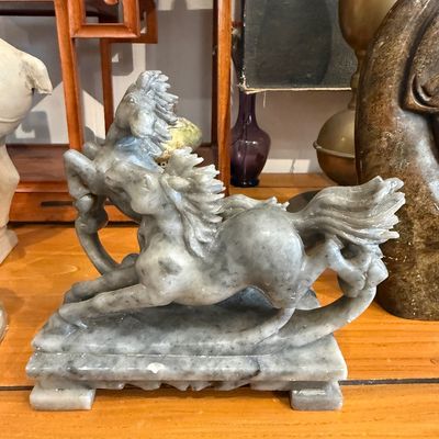 Carved grey soapstone or jadeite sculpture depicting two galloping horses on an integrated pedestal base.