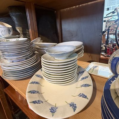 Collection of ceramic dinnerware featuring blue floral motifs, including stacked plates, small bowls, and a large oval serving platter...