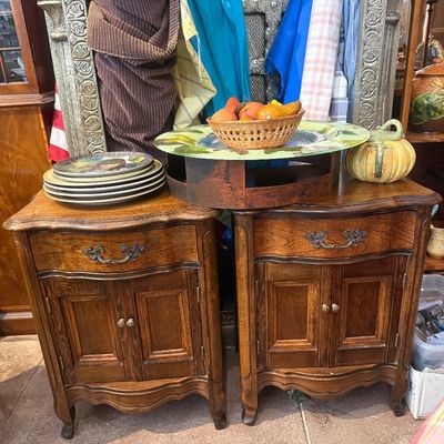 Pair of vintage French Provincial style oak nightstands or side cabinets with single drawers and double doors, holding decorative plates,...