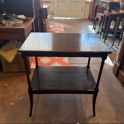 Vintage dark stain wooden two-tier side table with slender turned legs and flared feet.