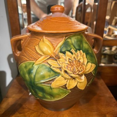 Vintage Roseville Pottery Water Lily pattern lidded cookie jar in brown, green, and yellow tones.