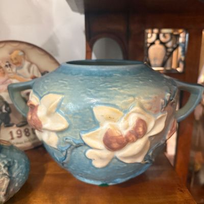 Vintage Roseville Pottery Magnolia double-handled vase in blue, featuring embossed white floral motifs.