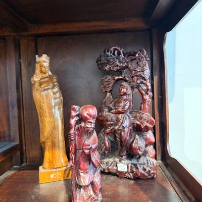 Collection of three hand-carved wooden figurines, including a Madonna and Child statuette alongside Asian motifs depicting an elder with...