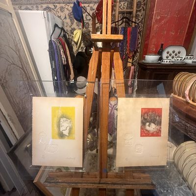 Pair of signed abstract prints mounted in acrylic frames, displayed on a tall wooden studio easel.