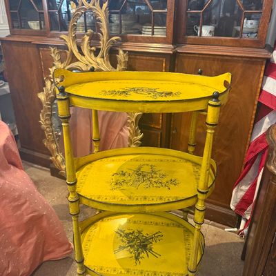 Vintage three-tier yellow painted tole tea cart with black floral transferware designs and faux bamboo posts.