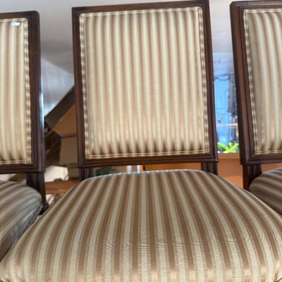 Set of Neoclassical style dining chairs featuring dark wood frames and beige striped fabric upholstery.