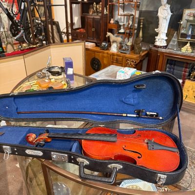 Full-size acoustic violin with a warm orange-brown finish, presented in a black hard case with blue plush lining and including a bow.