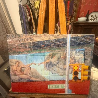 Contemporary mixed-media urban artwork depicting Michelangelo's 'Creation of Adam' mural on an easel, displayed alongside...