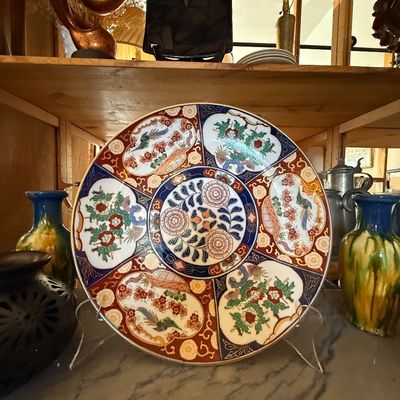 Large Japanese Imari porcelain charger featuring paneled floral and bird motifs in cobalt blue, rust red, and gilded accents.