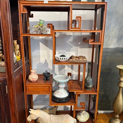 Chinese-style carved hardwood asymmetrical display shelf holding various decorative Asian antiques and collectibles, including ceramics,...
