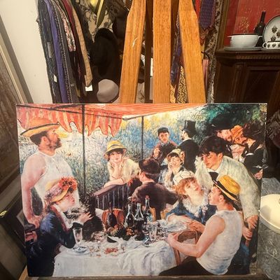 Framed print of Pierre-Auguste Renoir's "Luncheon of the Boating Party" displayed on a wooden artist's easel.