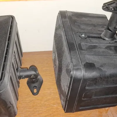 Sale Photo Thumbnail #263: Pair of black Bose 151 outdoor speakers featuring swivel mounting brackets, showing light dust from storage.