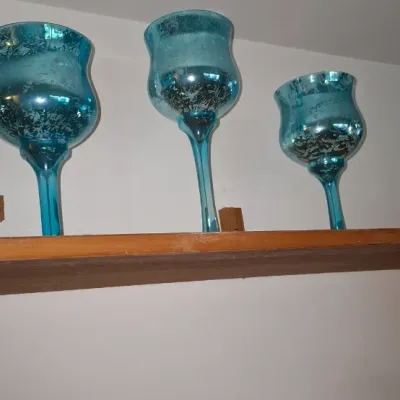Sale Photo Thumbnail #274: Set of three turquoise mercury glass stem candle holders of varying heights, displayed on a wooden shelf.