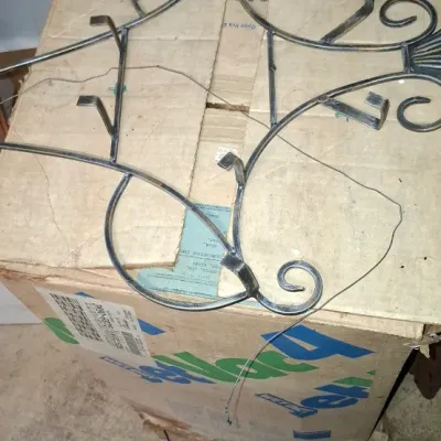 Sale Photo Thumbnail #231: Black wrought iron decorative wall hanger with scrollwork details, resting on top of a cardboard box.