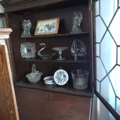Sale Photo Thumbnail #242: Traditional Chippendale style mahogany secretary desk with a broken-pediment top finial, glass-door hutch containing crystal glassware, and a slant-front writing surface over lower drawers.