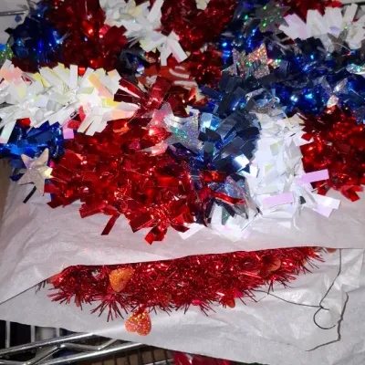 Sale Photo Thumbnail #184: Patriotic red, white, and blue tinsel wreath stored alongside a red glitter heart wreath on wire shelving.