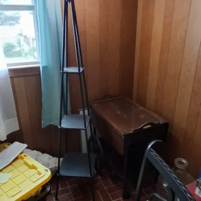 Black metal torchier floor lamp with integrated square display shelves alongside a wooden rolling tea cart.