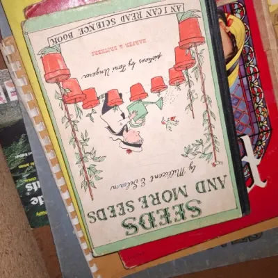 Stack of vintage children's books and publications, featuring a 1959 edition of "Seeds and More Seeds" by Millicent E....