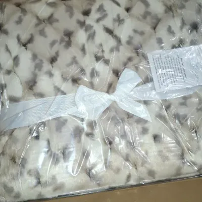 Sale Photo Thumbnail #152: New in box faux fur plush throw blanket wrapped in plastic packaging with a white ribbon tie.