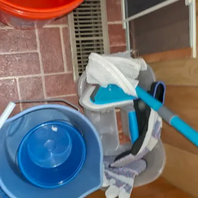 Collection of household cleaning supplies including plastic buckets, a mop, mesh bags, and work gloves.