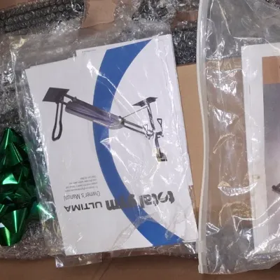 Sale Photo Thumbnail #211: Boxed Total Gym exercise equipment featuring wrapped components, a green gift bow, and two printed owner's manuals.