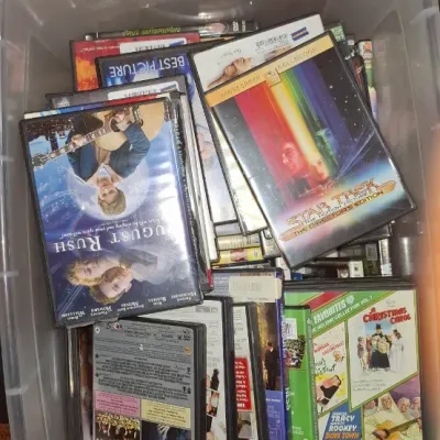 Clear plastic storage tote filled with assorted DVD movies, including titles like Star Trek: The Motion Picture and August Rush.