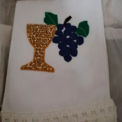 Hand-crafted white linen altar cloth featuring a sequined golden chalice, felt grape motif, and crocheted fringe trim.